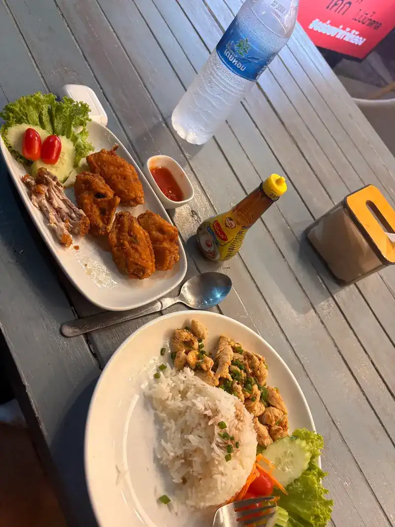 A fried plate with chilli sauce, and rice with a stir-fry, on a wooden table