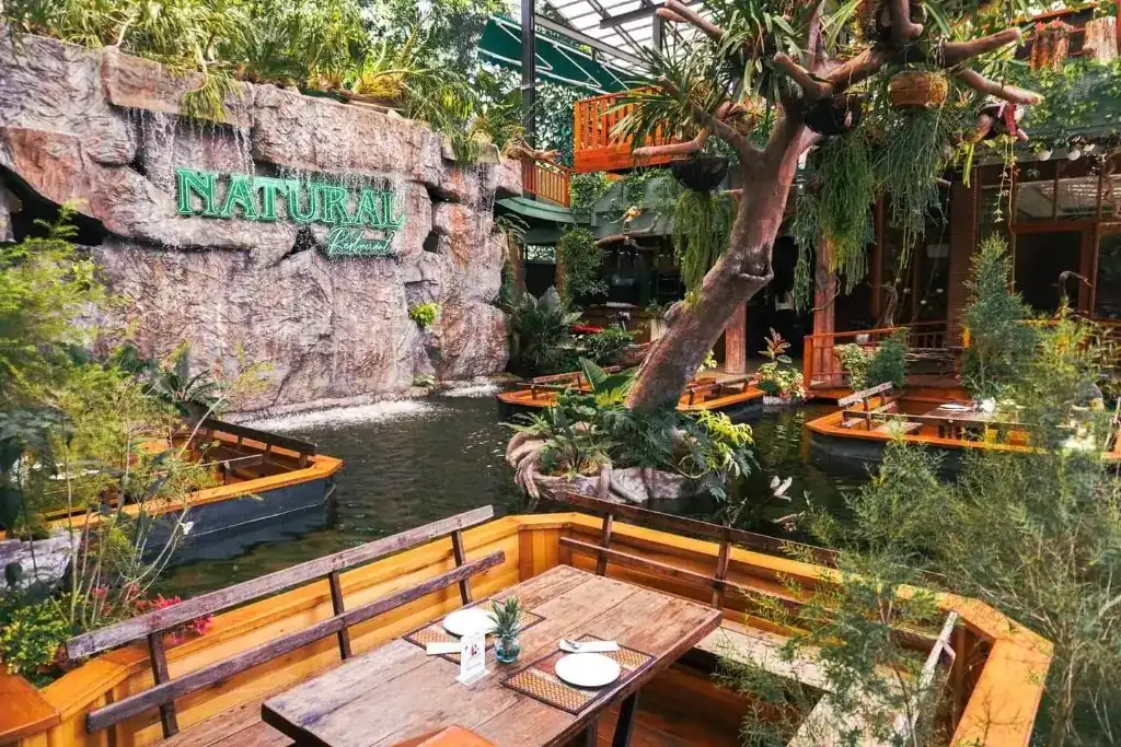 Wooden boat tables floating on the pond below the waterfall at Natural Restaurant