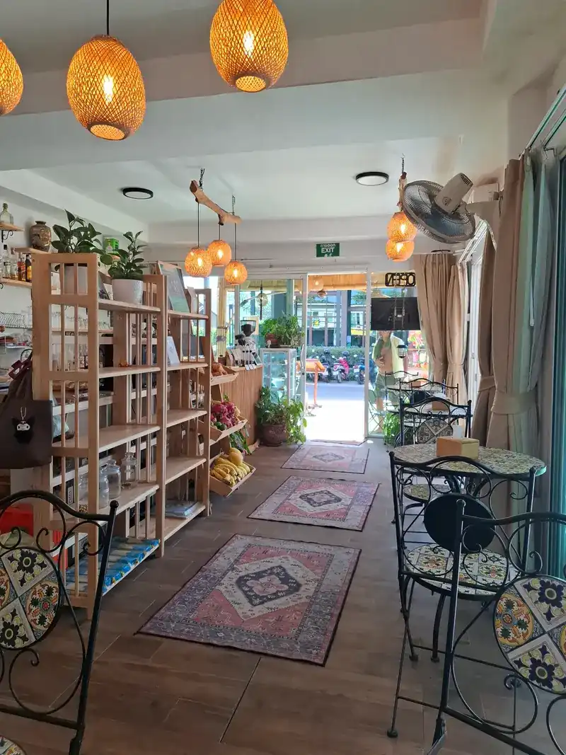 Inside the café: patterned rugs, wooden shelves, rattan lamps and tiled tables