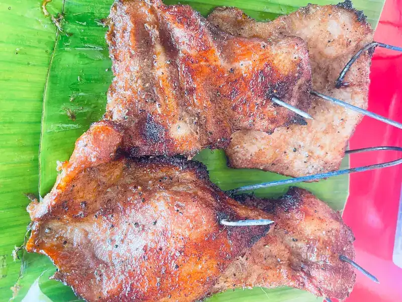 Chargrilled meat on skewers, laid on a banana leaf