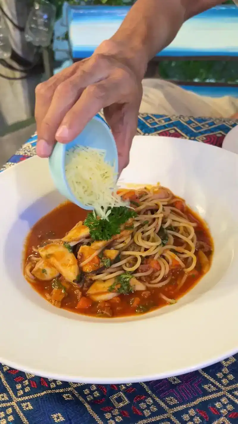 Grated cheese going onto spaghetti in tomato sauce