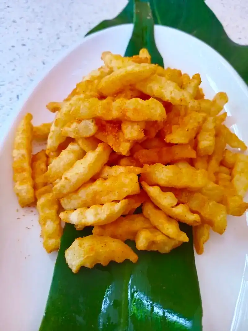 Crinkle-cut fries with a dusting of seasoning, on a leaf