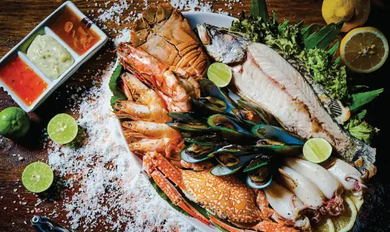 Seafood platter with prawns, crab, mussels, squid and fish on salt, with dipping sauces and lime