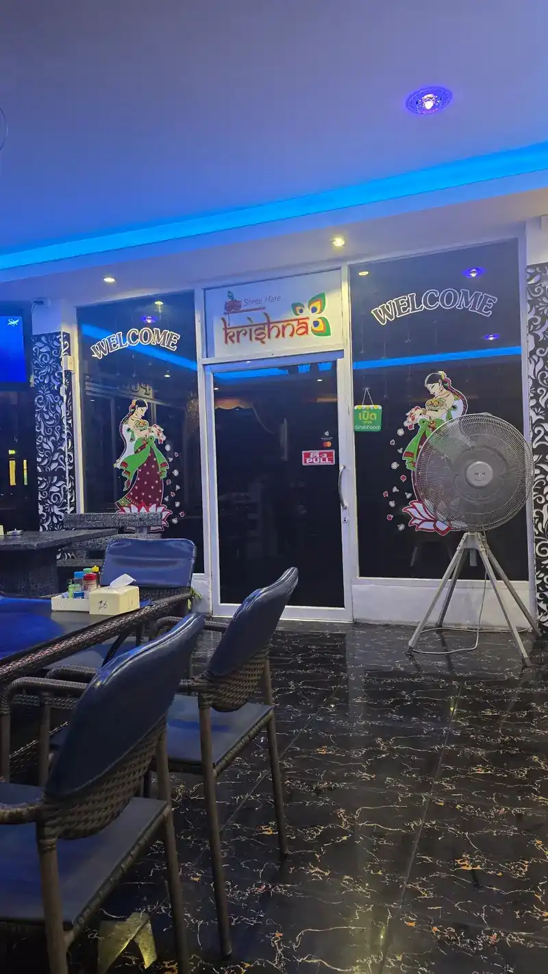The front door at night: blue light, WELCOME on the glass and the Krishna sign