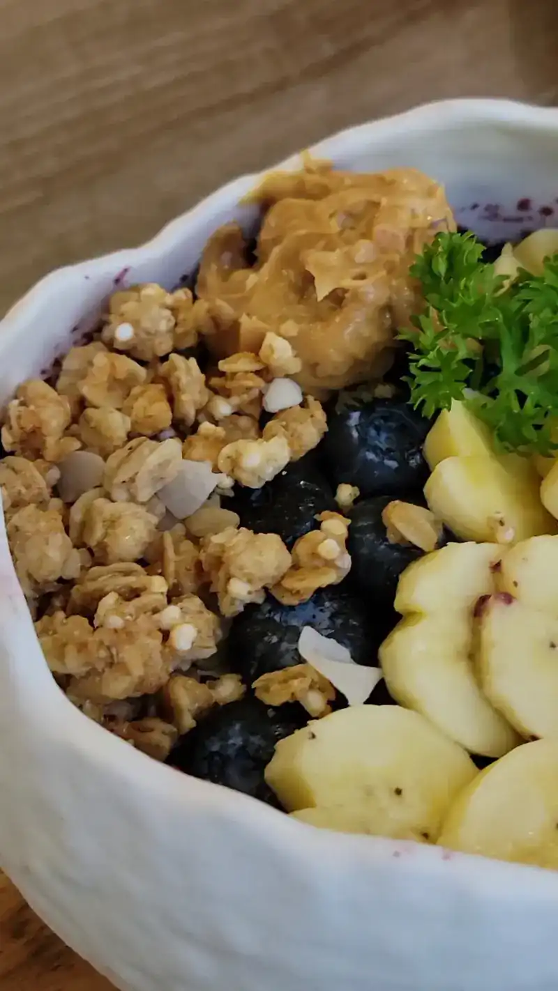 Fruit bowl topped with granola, blueberries and banana