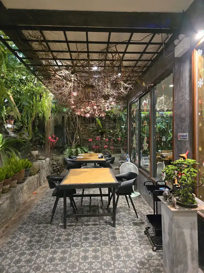 A glass-walled dining room lined with plants, with tables on a patterned tile floor