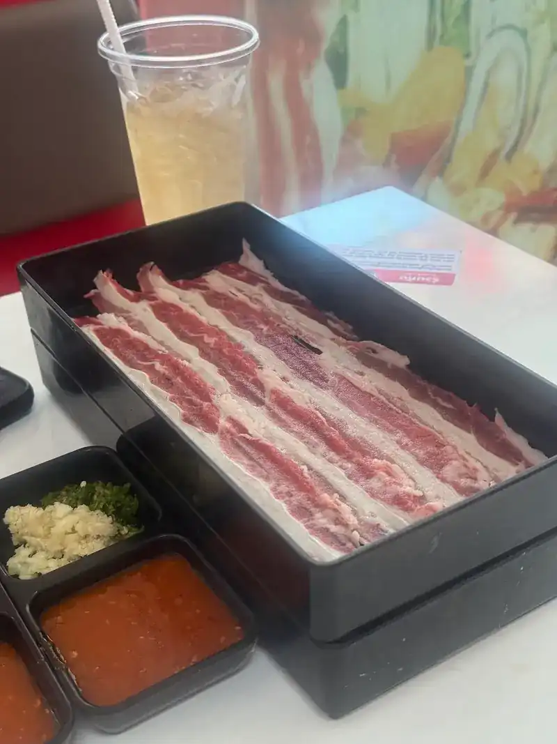 A tray of thin-sliced beef with dipping sauces
