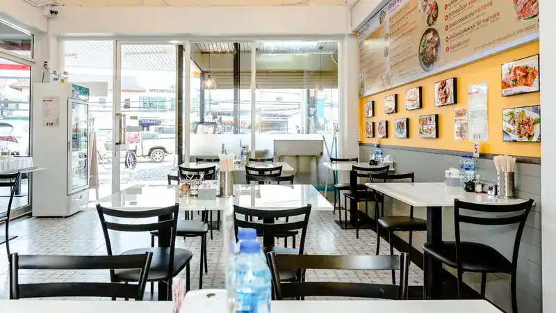 The dining room: white tables, black chairs and a yellow wall hung with framed dish photos