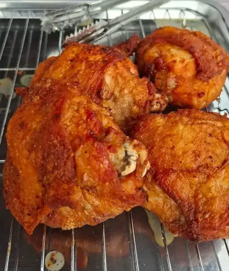 Four large pieces of fried chicken, deep gold, on a wire rack