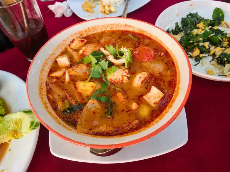 A large bowl of red tom yum with seafood