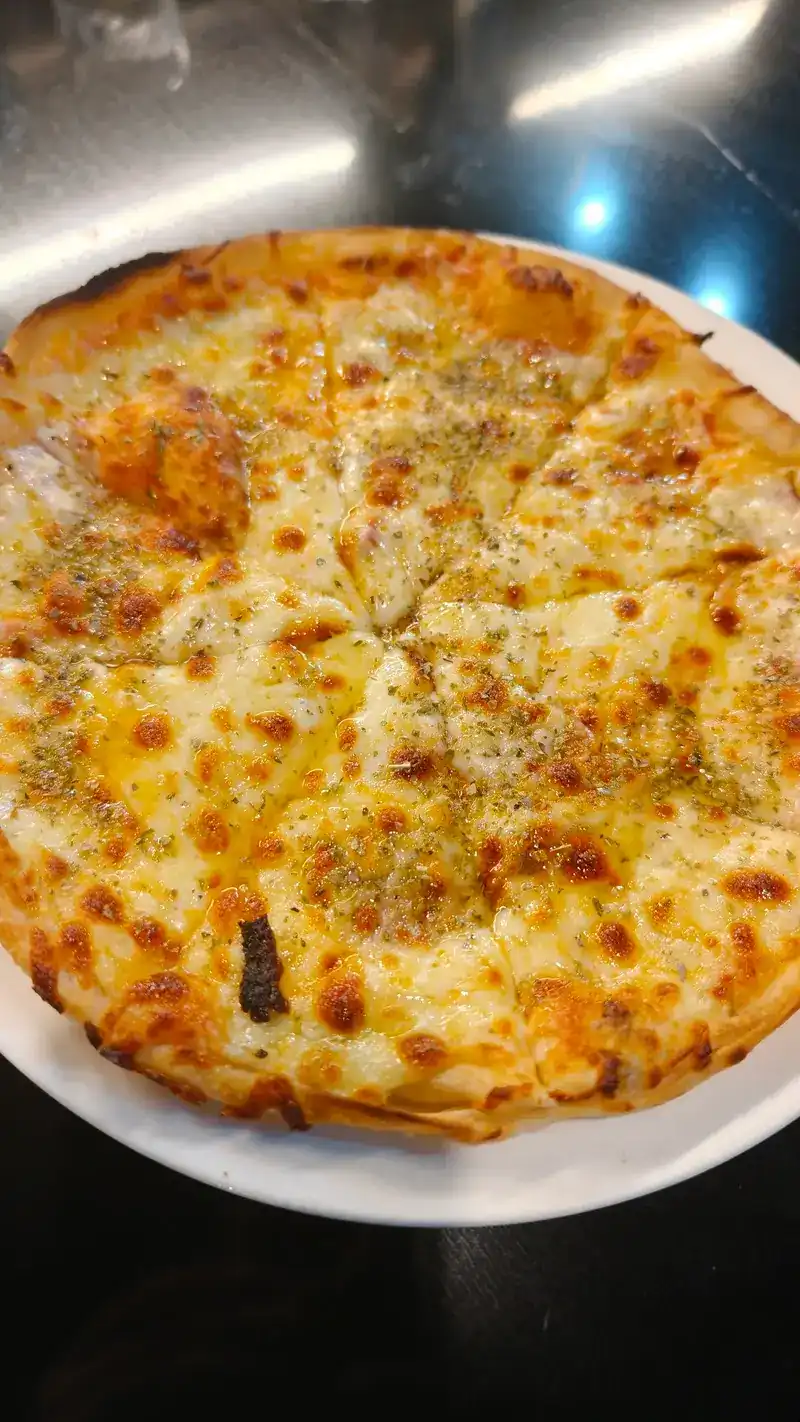 A round pizza with golden melted cheese and dried herbs