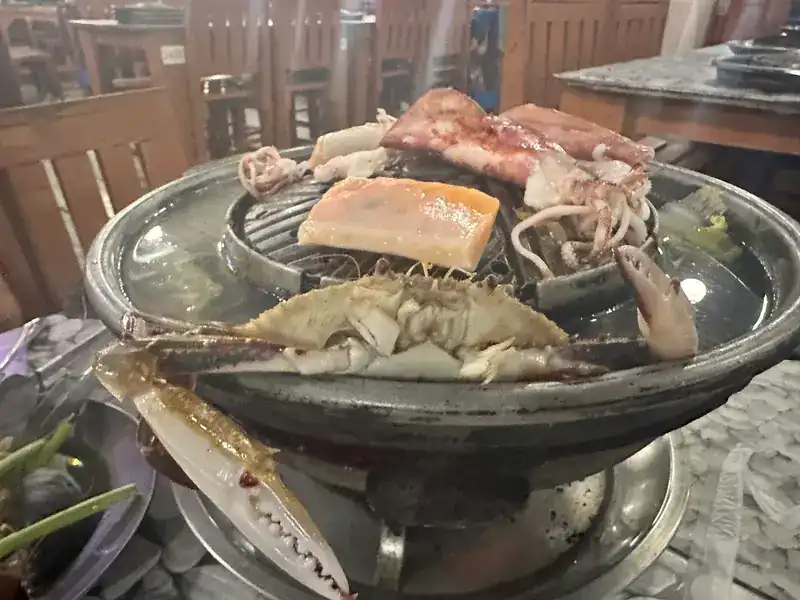 Crab, squid and a block of pork fat on a mookata pan