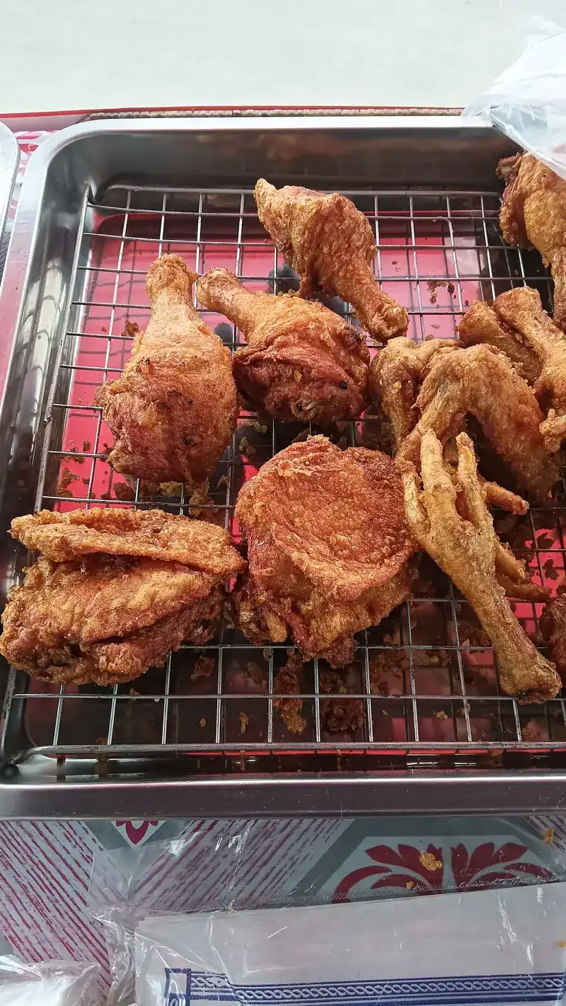 Drumsticks, thighs and wings of fried chicken on a wire rack over a red tray