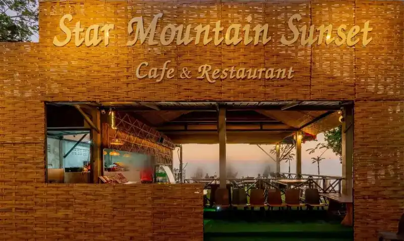 The woven bamboo front with the Star Mountain Sunset sign at dusk, the terrace and the sunset seen through the opening
