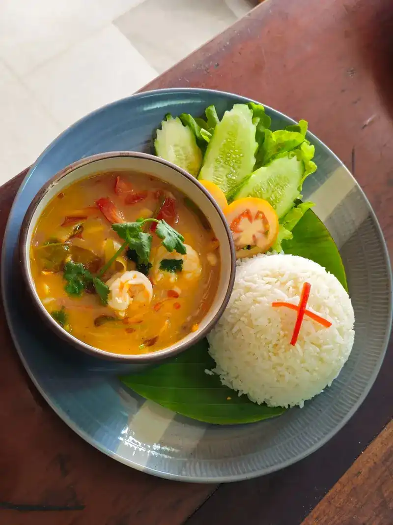 A bowl of Thai shrimp soup with jasmine rice and fresh vegetables