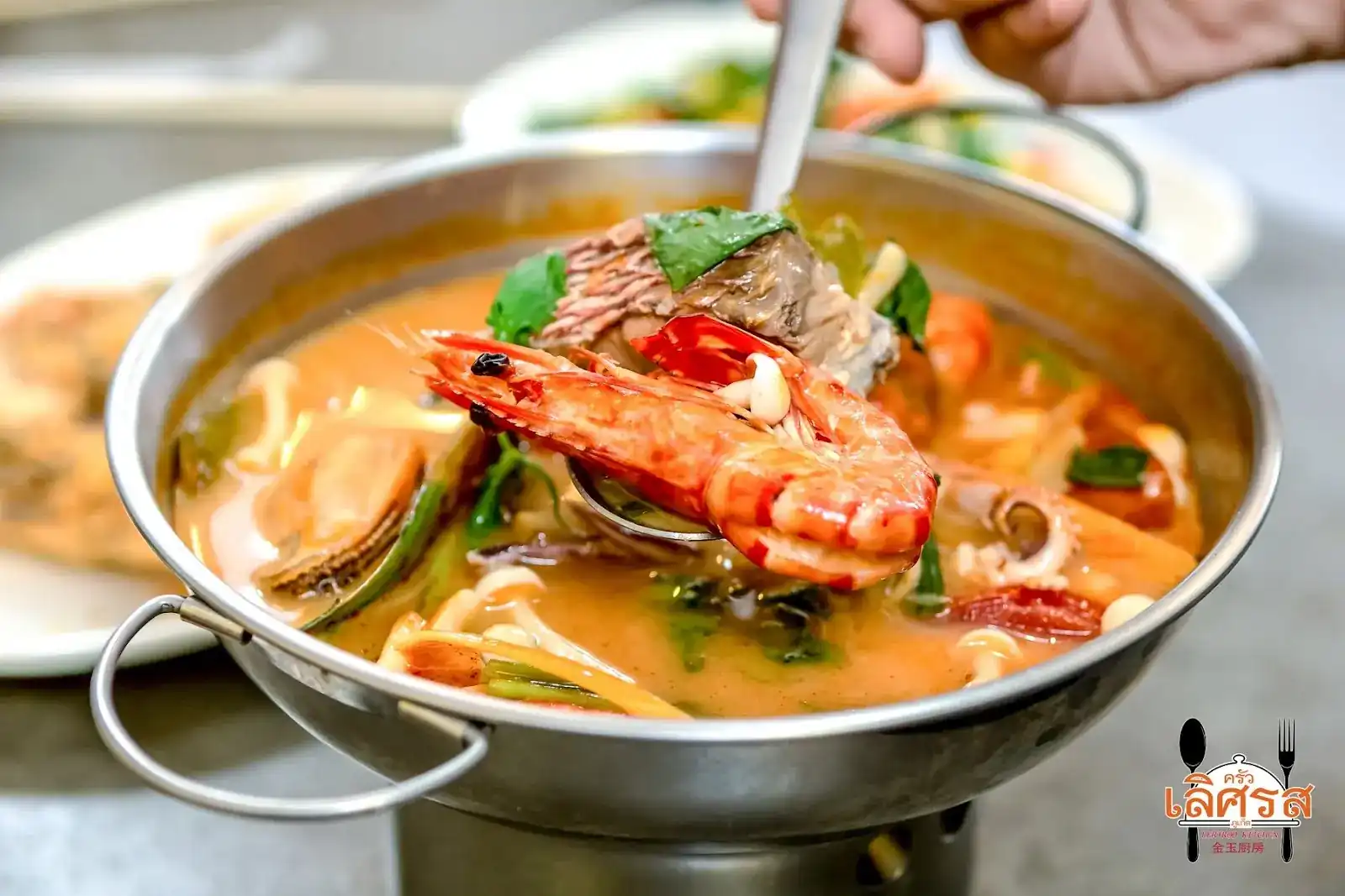 Seafood tom yum with a whole prawn, served in a pot over a burner