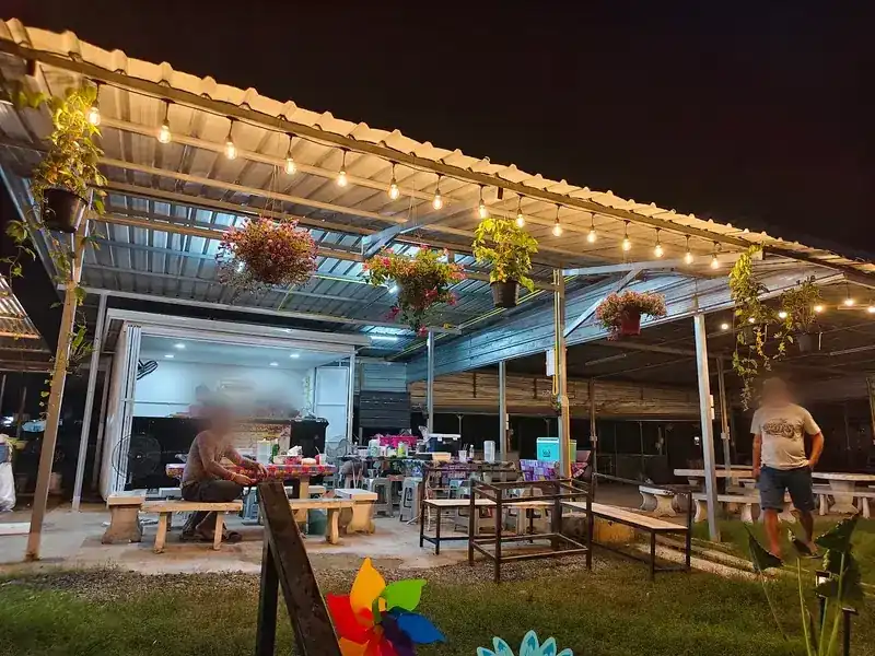 The open-air tables and kitchen at night, under string lights