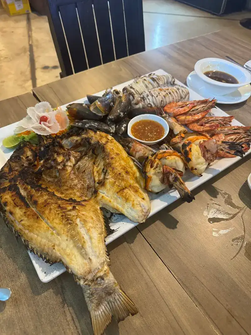 A long seafood platter: grilled whole fish, squid, mussels and prawns with a dipping sauce