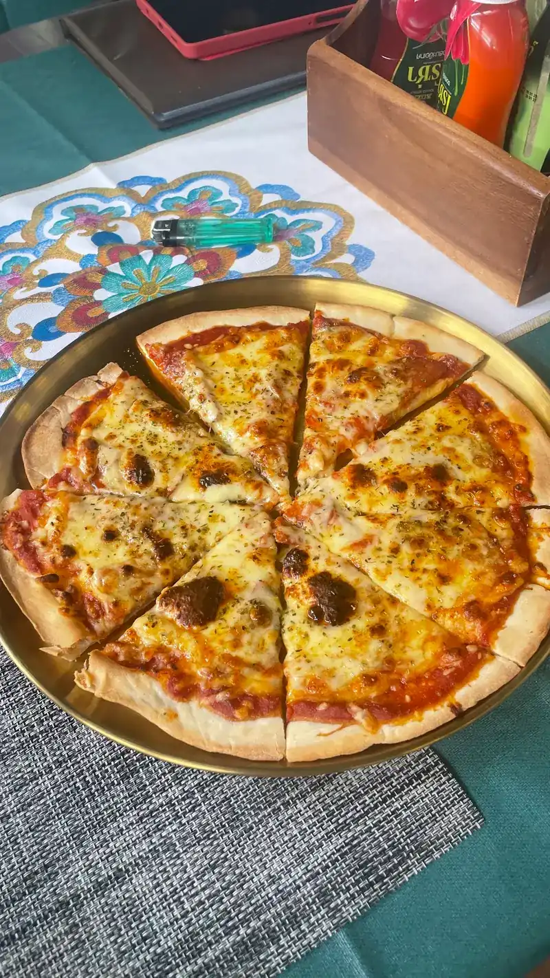 A cheese pizza cut into slices on a round metal tray