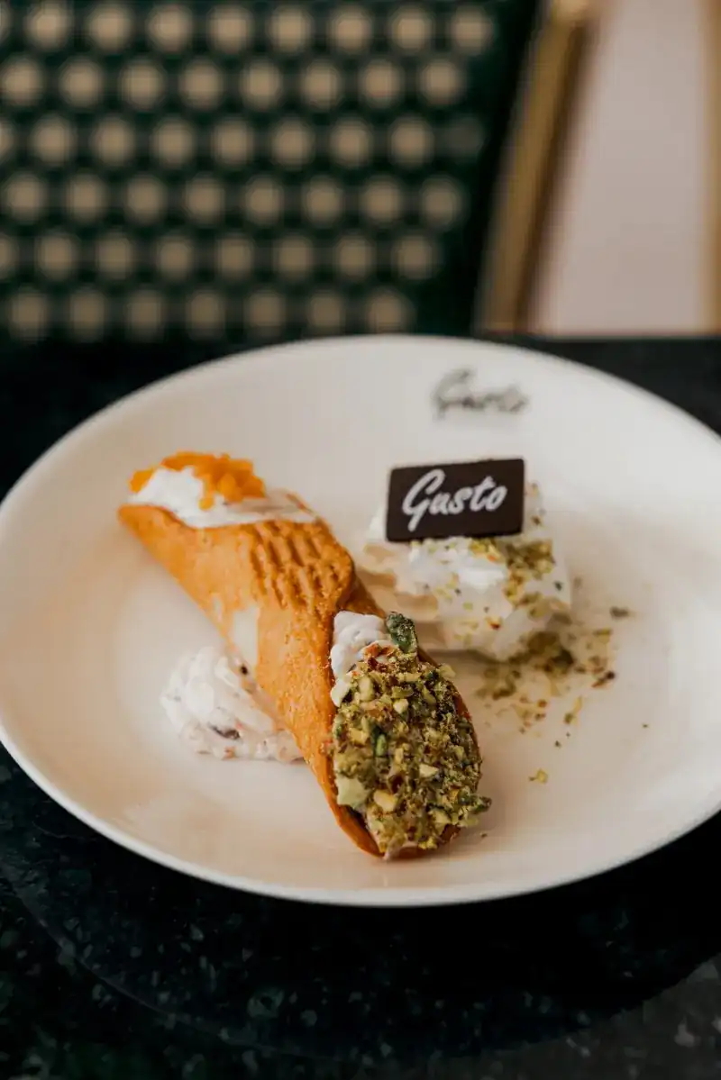 A cannolo with pistachio and candied orange on a Gusto plate