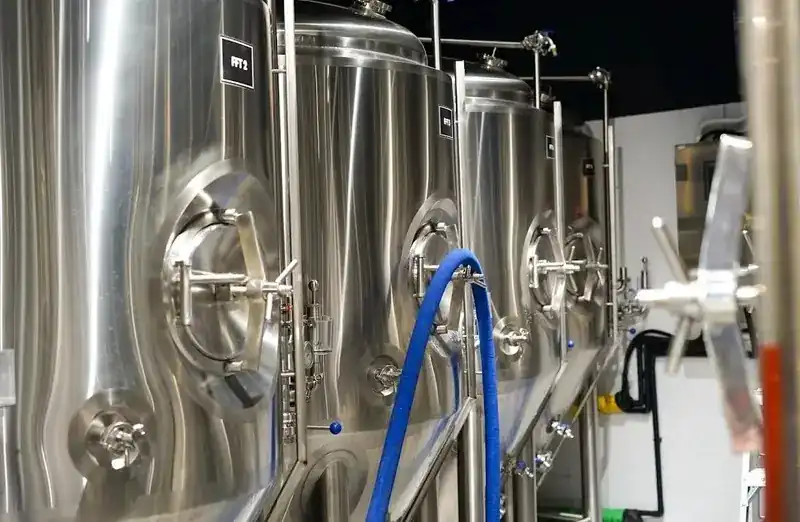 A row of stainless-steel fermentation tanks at Bearfest with a blue hose running between them