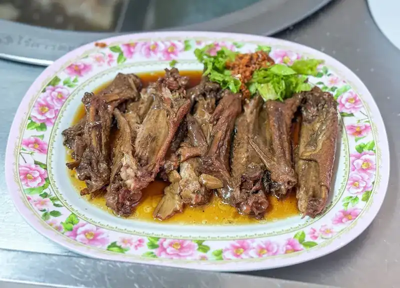 Stewed duck wings in braising sauce on a flowered plate / ปีกเป็ดตุ๋นราดน้ำพะโล้บนจานลายดอกไม้