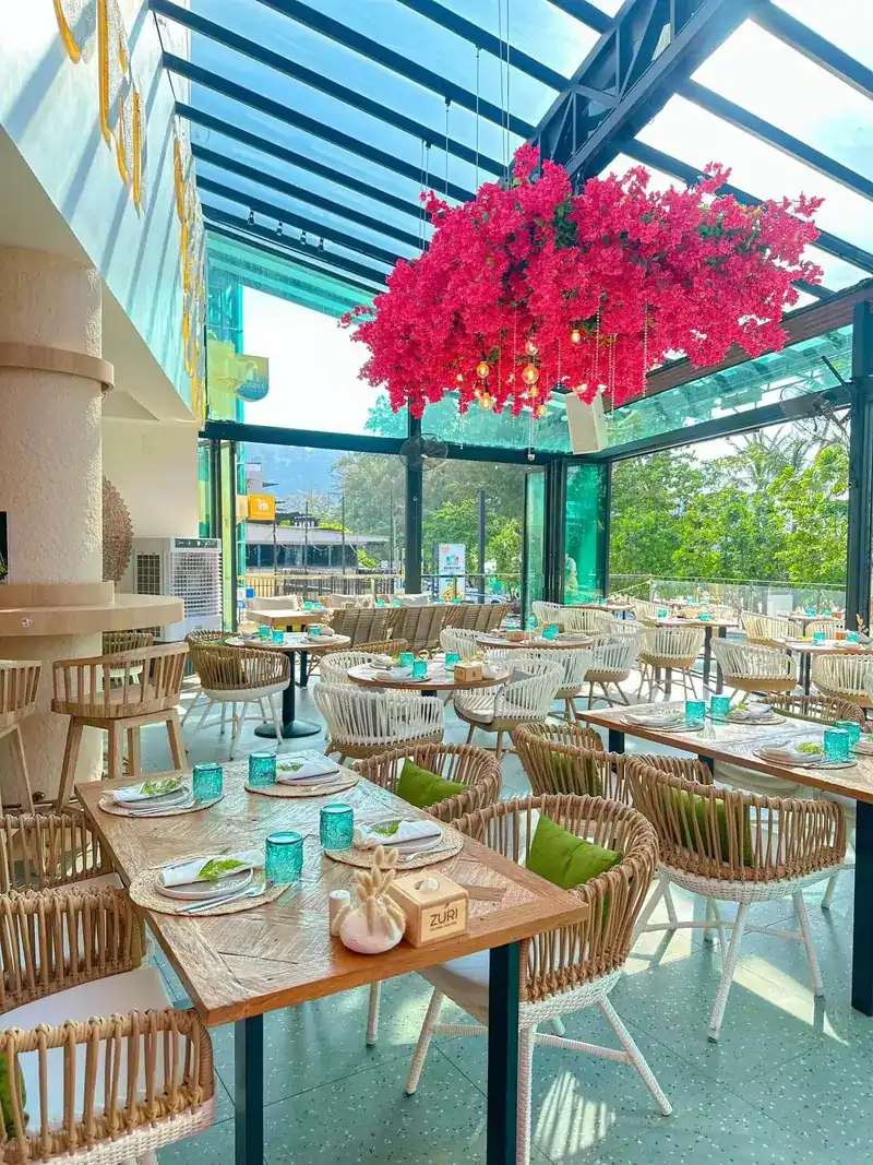 Rows of rattan chairs on the terrace beneath the hanging flowers