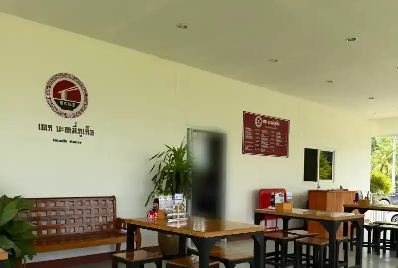 Inside the hall: the shop's sign on a white wall, a wooden bench and tables