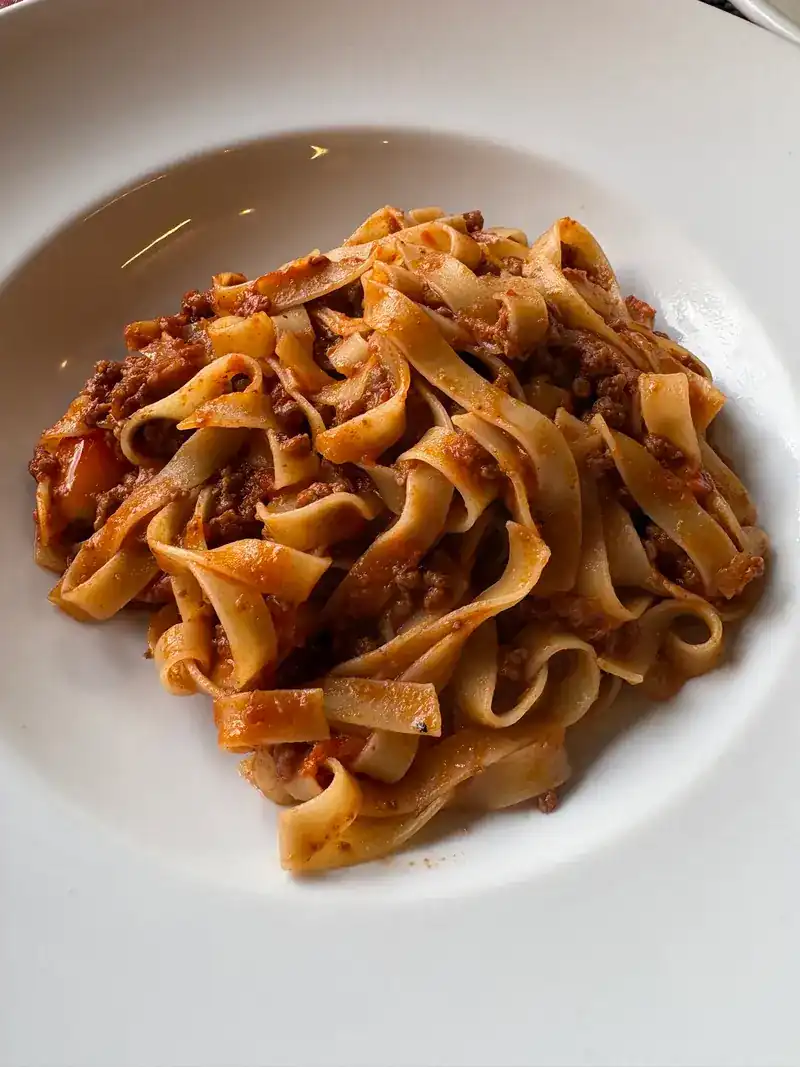 Ribbon pasta in a meat sauce in a wide white bowl