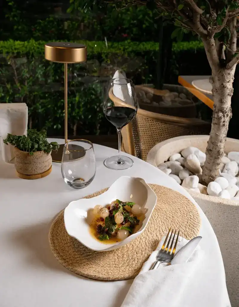 An evening table with a small dish, a candle lamp and a planter of white pebbles