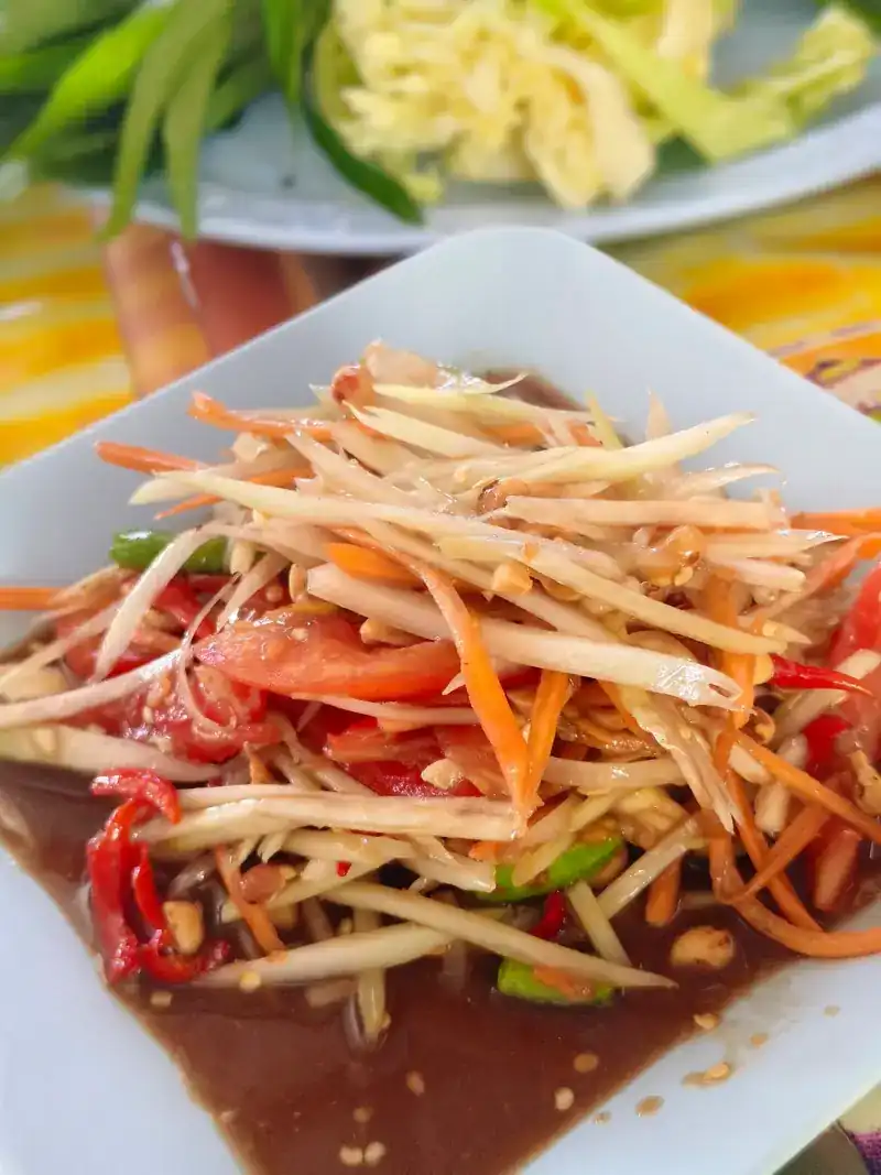 A plate of papaya salad with tomato and chilli