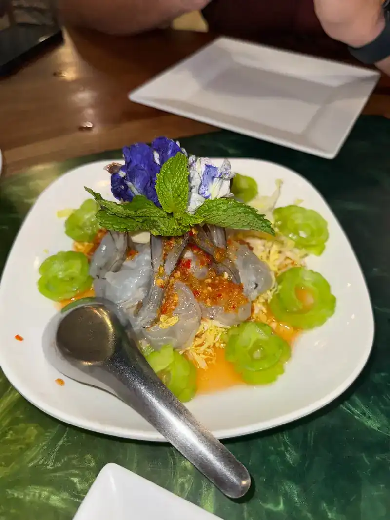 Prawns in a chili dressing, ringed with carved green vegetables and topped with blue flowers and mint
