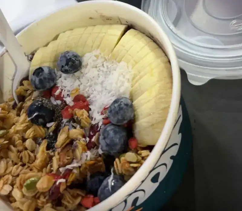 Bowl of granola topped with banana, blueberries and grated coconut