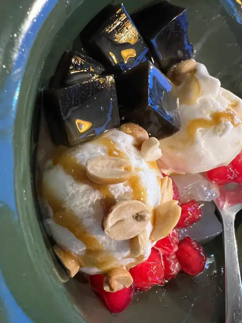 Grass jelly with scoops of ice cream, peanuts and red jelly