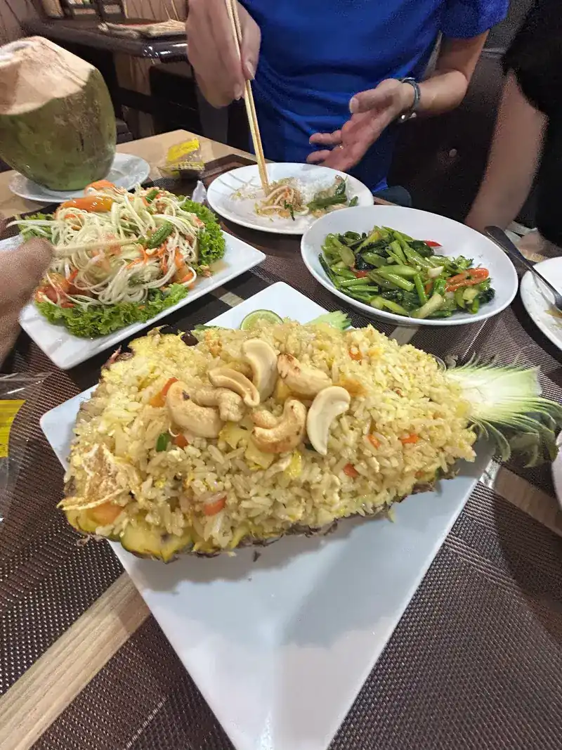 Pineapple fried rice with cashew nuts served in the pineapple, with papaya salad and stir-fried greens / ข้าวผัดสับปะรดใส่เม็ดมะม่วงหิมพานต์เสิร์ฟในลูกสับปะรด กับส้มตำและผัดผัก