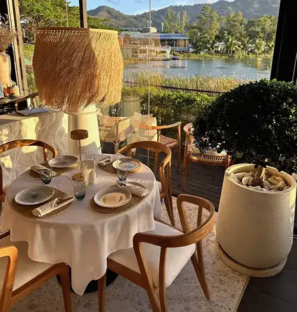 A round table set for four on the terrace, the lagoon and hills behind