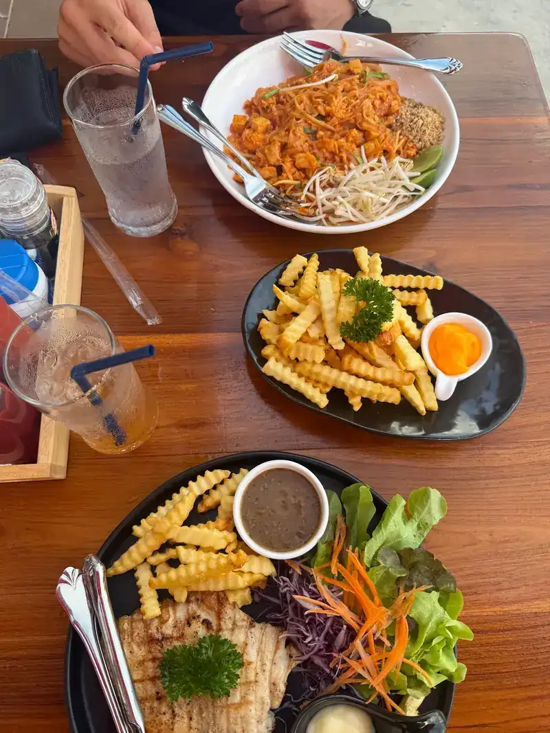 One table's order from above: pad thai, a plate of crinkle-cut fries and a grilled steak plate with salad