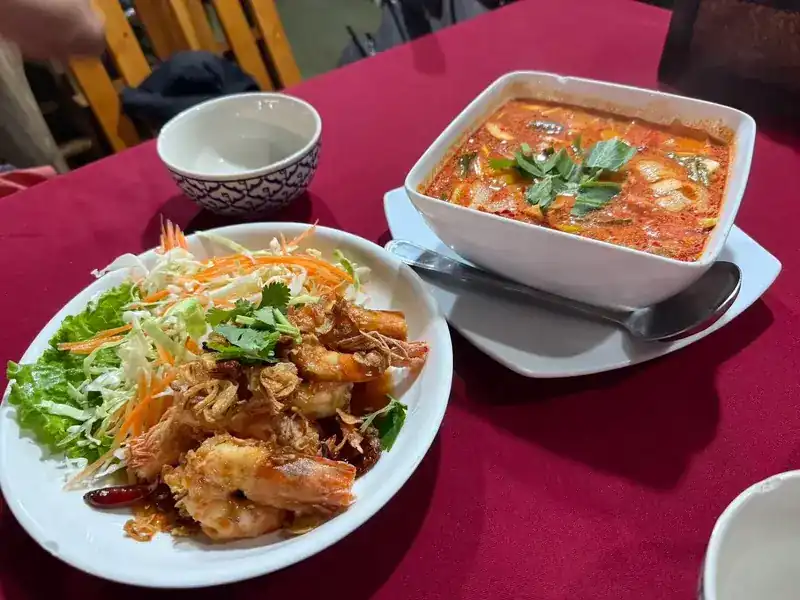 Prawns with dried chillies and fresh salad, a bowl of tom yum behind