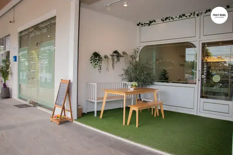 The shop front with a wooden table and bench on the grass outside