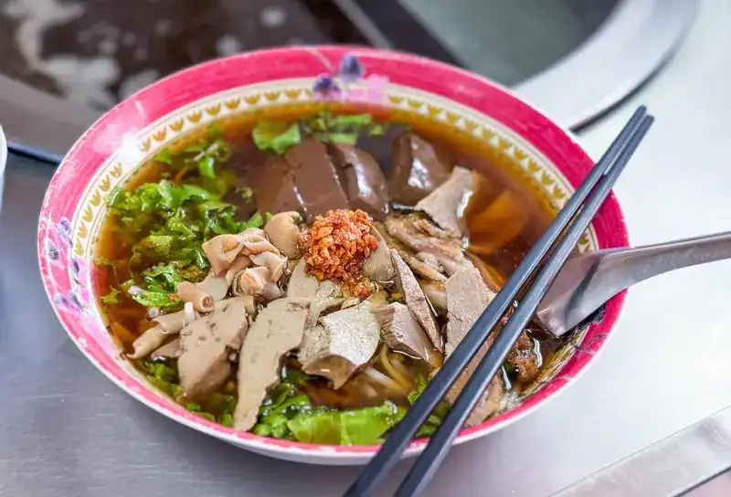 Duck noodle soup with sliced duck, offal, greens and fried garlic / ก๋วยเตี๋ยวเป็ดพะโล้น้ำ ใส่เนื้อเป็ด เครื่องใน ผัก และกระเทียมเจียว