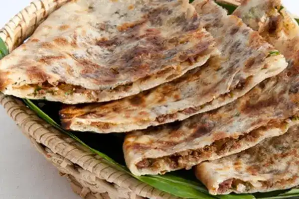 Stuffed flatbreads in a basket lined with banana leaf