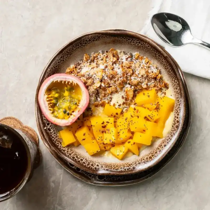 A bowl of granola with mango and passion fruit