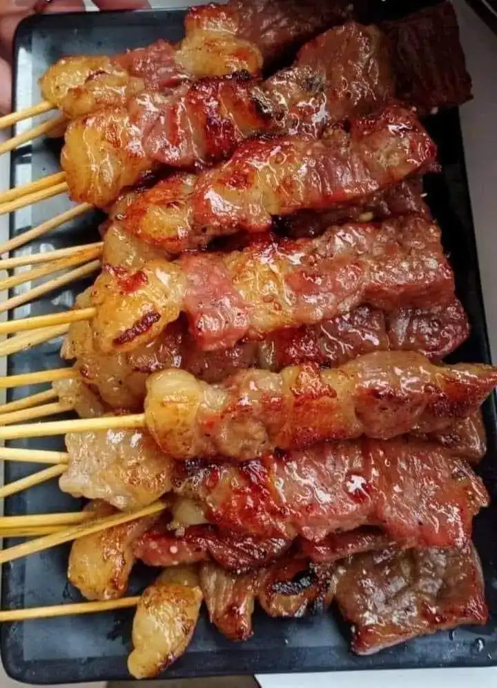A tray of glossy grilled skewers, charred at the edges