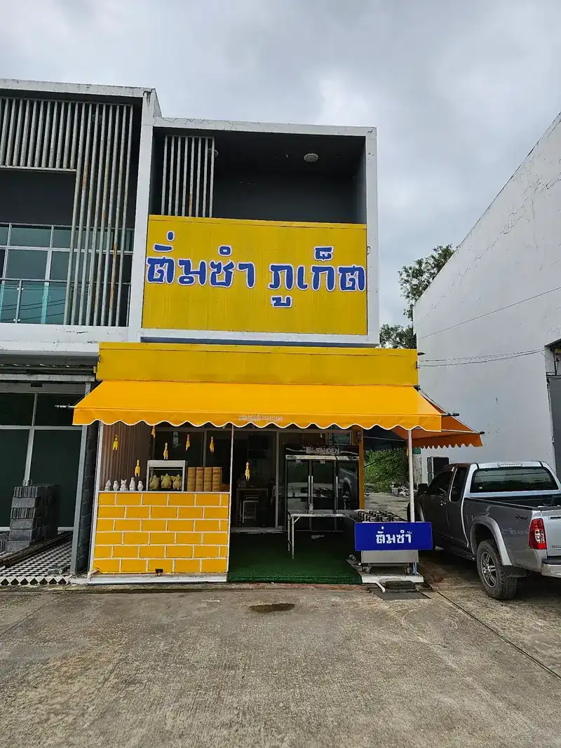 The shop front: a yellow shophouse with a yellow awning and a blue-lettered sign