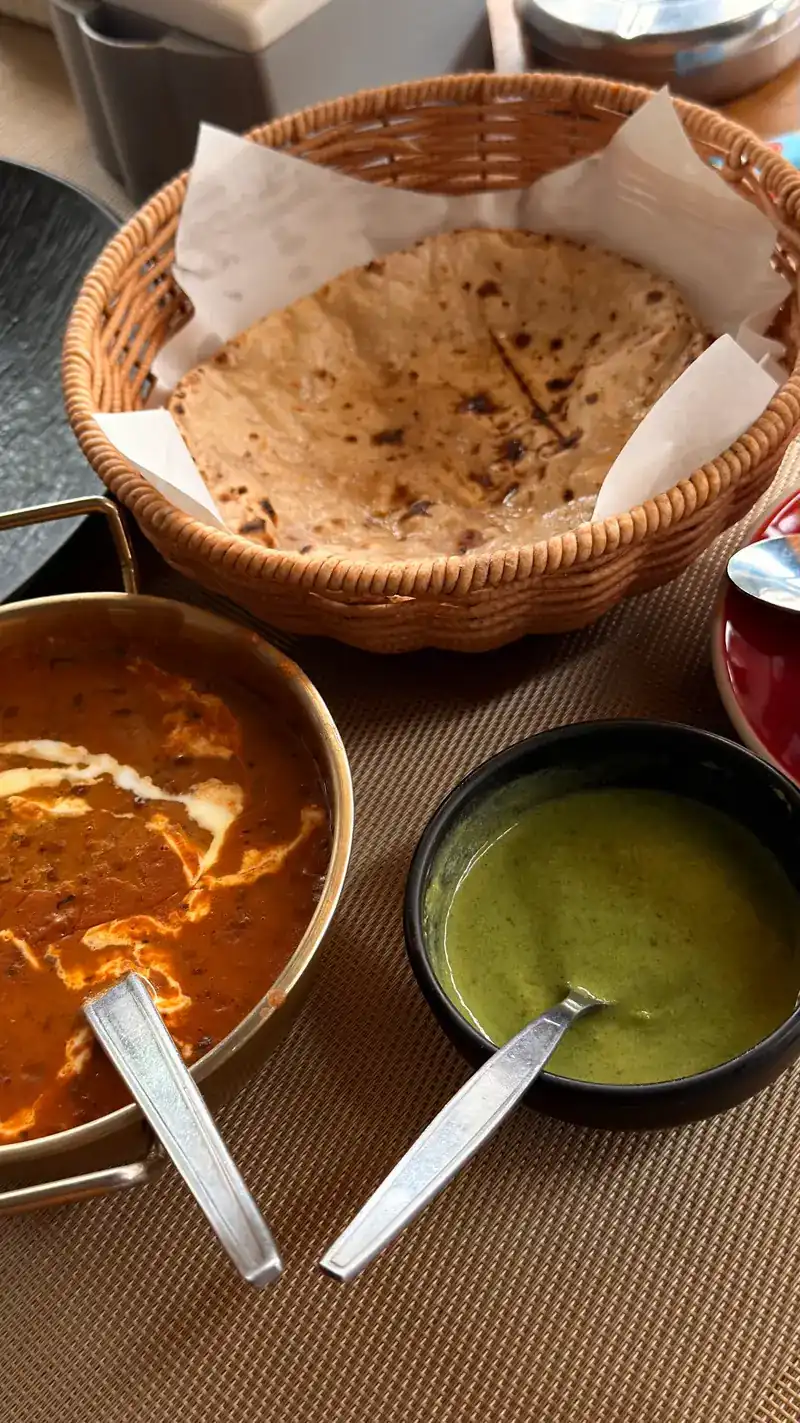 A basket of roti with a creamy curry and green chutney