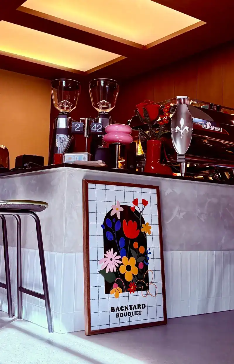 The coffee counter with two grinders, an espresso machine and red flowers