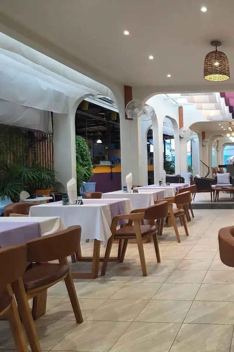 The covered dining room, white tablecloths and wooden chairs