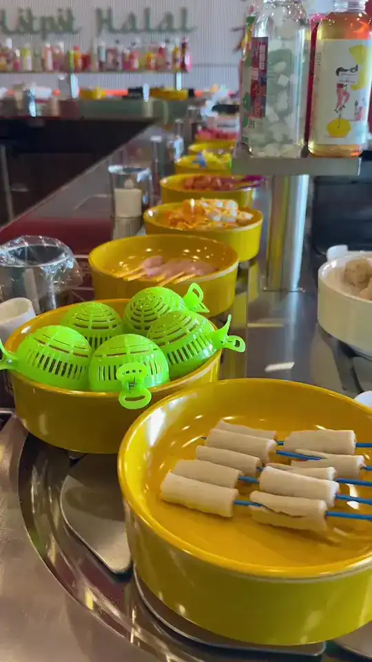 Yellow bowls with strainer ladles and skewers riding the belt