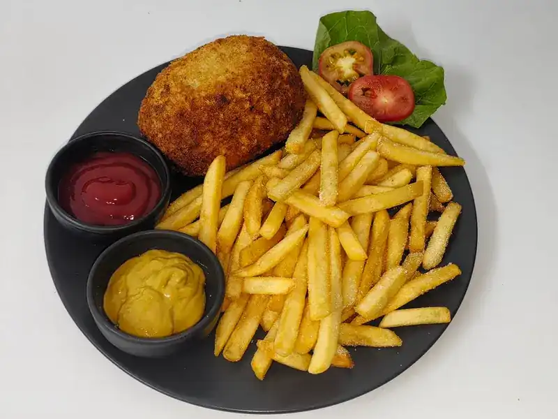 A crumbed cutlet with fries, ketchup and mustard
