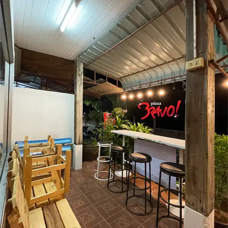 The covered terrace at night, with the pizza Bravo! sign on the back wall